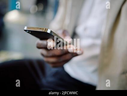 Closeup of Black businessman travelling in a train while using a cellphone. African american male using a wireless device while commuting on a train Stock Photo