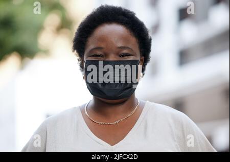 A african-american woman woman wearing a protective face mask while out in the city. A african-american woman woman wearing a protective face mask Stock Photo