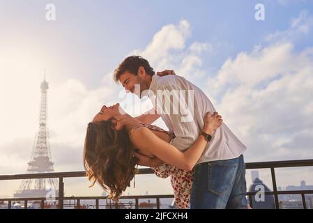 When in Paris.... Shot of a young couple sharing a romantic moment on the balcony of an apartment overlooking The Eiffel Tower in Paris, France. Stock Photo