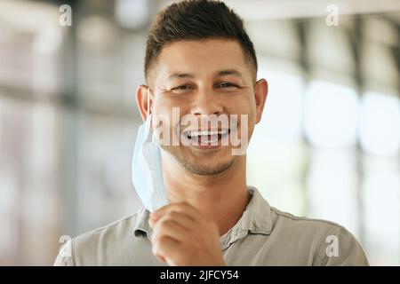 Portrait of business man removing protective face mask off his face to breath freely in the office during COVID-19 Stock Photo