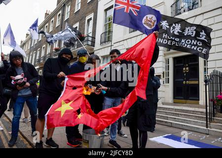 London, UK. 01st July, 2022. Protesters are seen burning the Chinese flag at the rally outside the Hong Kong Economic and Trade Office. Hundreds of Hongkongers residing in London gathered on the 25th anniversary of the handover of Hong Kong to protest against the authoritarian regimen by the Chinese Community Party. Credit: SOPA Images Limited/Alamy Live News Stock Photo
