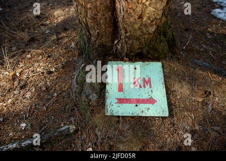 A sign indicating the length of the tourist route 1 kilometer lying on ...
