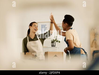 Diverse colleagues unite with high five. Two fashion designers celebrating together. Cheerful tailors collaborate and motivate each other. Two Stock Photo