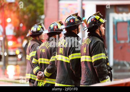 Seattle - June 30, 2022; Seattle firefighters in high visibility uniforms stand in a line waiting to work on an active fire Stock Photo