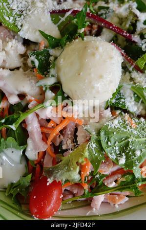 A cobb style salad with chicken, ham and egg sprinkled with creamy cheese dressing and parmesan cheese Stock Photo