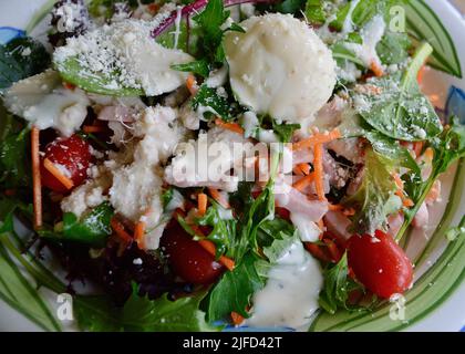 A cobb style salad with chicken, ham and egg sprinkled with creamy cheese dressing and parmesan cheese Stock Photo