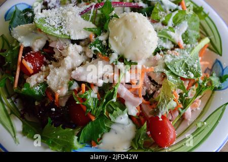 A cobb style salad with chicken, ham and egg sprinkled with creamy cheese dressing and parmesan cheese Stock Photo