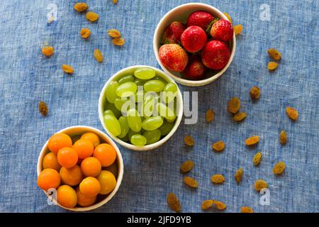 Fruit bowl with assorted mix of fresh,juicy Cape Gooseberries,Grapes and Strawberries,isolated on dark rustic background.Backlit,closeup,vegan concept Stock Photo