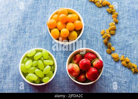 Fruit bowl with assorted mix of fresh,juicy Cape Gooseberries,Grapes and Strawberries,isolated on dark rustic background.Backlit,closeup,vegan concept Stock Photo