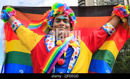 London, UK. 02nd July, 2022. A participant proudly poses with the rainbow flag during the build up at Park Lane. Participants and spectators have fun along the route of the Pride in London 2022 Parade. The parade progresses from Hype Park along Piccadilly to Whitehall this year. the Pride movement and the LGBT  community commemorates 50 Years since the first Pride took place in the United Kingdom. Credit: Imageplotter/Alamy Live News Stock Photo