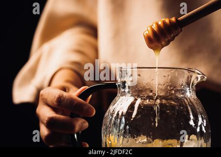 Adding honey to chilled citrus fruits in glass jars, cool and fruity cold drink making process - stock photo Stock Photo