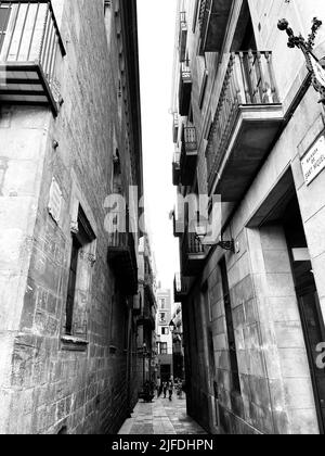A vertical grayscale shot of a narrow street between buildings Stock ...