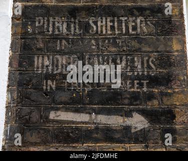 London, UK - April 20th 2022: Historic ghost signs on a street in Westminster, London, dating from the 2nd World War, informing the location of the ne Stock Photo