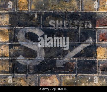 London, UK - April 20th 2022: Historic ghost signs on a street in Westminster, London, dating from the 2nd World War, informing the location of the ne Stock Photo