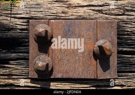 An abandoned old railway tie with a rusty bolt on an old cracked wooden railway sleeper, top view. Stock Photo