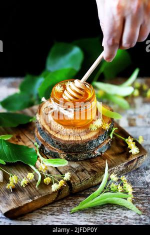 Linden honey in a jar. Leaves and flowers of linden. Freshly linden honey. Stock Photo