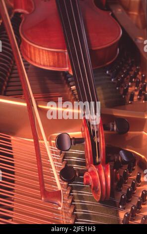 A  old Violin and bow laying on a Piano Stock Photo
