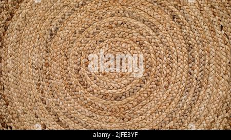 Round natural raffia rug with a spiral braided design and concentric circles that creates an ideal texture for backgrounds and graphic resources. Stock Photo