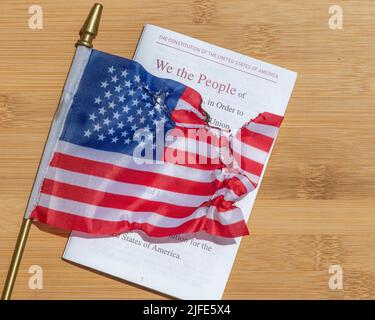 Close up of a burned American flag laying on top of the Constitution of the United States. Stock Photo