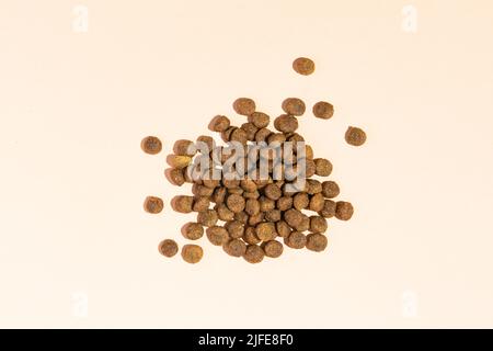 A handful of dry food for cats and dogs on a beige background. View from above Stock Photo