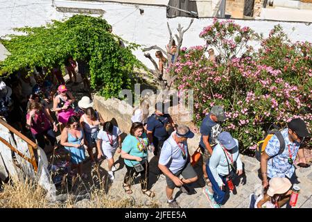 Lindos, Rhodes, Greece - May 2022: Visitors climbing the steps to reach the town's ancient acropolis Stock Photo