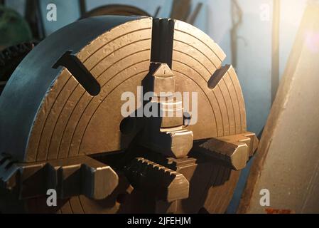 Closeup of an old Lathe Machinery. lathe chuck and key 4-jaw screw chuck. Vintage Industrial Machinery in a old factory. Stock Photo