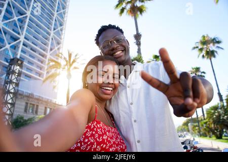 Selfie of a young black couple looking at camera smiling. Concept of vacation and relationship. African American couple having fun enjoying holidays Stock Photo