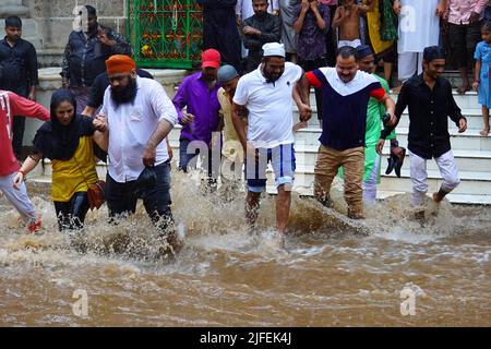 Indian People wade through a waterlogged street after a heavy monsoon ...