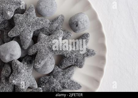 Salty liquorice salmiakki in Finnish in a white plate top view Stock Photo