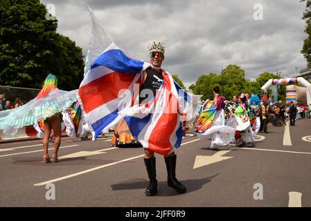 A Gay man parades along Park Lane, Central London, in an exotic costume incorporating the Union Jack flag during celebrations to mark the 50th anniversay of Pride. Stock Photo