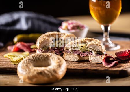 Bagel filled with juicy beef pastrami together with pickles. Stock Photo