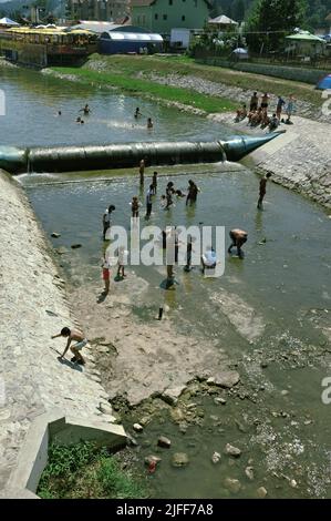 gypsy community cooling off and catching small fish by the hands in the shallow waters of the Bjelica river in Guca, Serbia Stock Photo