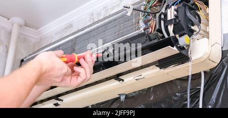A man disassembles an air conditioner for repair and cleaning. Split system maintenance. Stock Photo