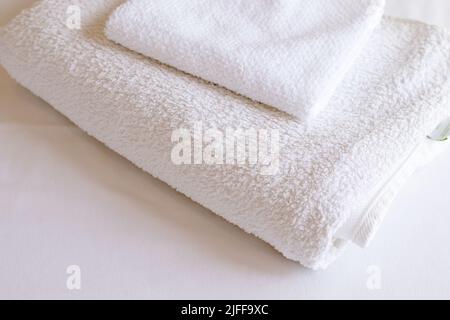 White folded clean towels on the hotel bed, Cleaning, laudry and washing towels at home. Stock Photo