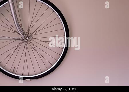 Bicycle wheel hanging on the wall with copy space. Wall mounted bike storage in the apartment Stock Photo