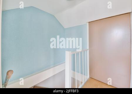 Hallay with blue and pink walls and white stairs leading down Stock Photo