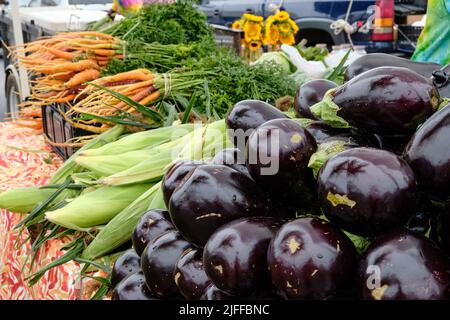 Fresh corn, eggplant and carrots being sold at a fresh vegetable and produce stand by a local farmer at the Montgomery Alabama farmers market. Stock Photo