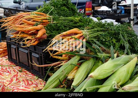 Fresh corn and carrots being sold at a fresh vegetable and produce stand by a local farmer at the Montgomery Alabama farmers market. Stock Photo