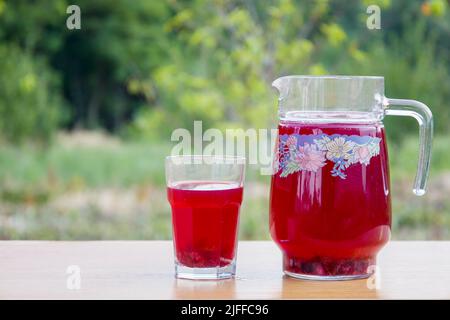 Red compote of berries in a glass and jug Stock Photo
