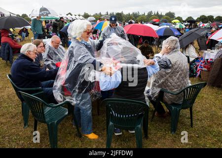 Woodstock, Oxfordshire, UK. 2nd July 2022. Two women putting on a disposable rain poncho. Battle Prom Picnic Concerts. Blenheim Palace. United Kingdom. Credit: Alexander Caminada/Alamy Live News Stock Photo