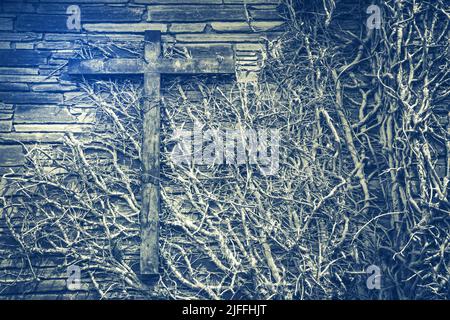 Old wooden cross on a wall covered with dry ivy, abstract vintage concept Stock Photo