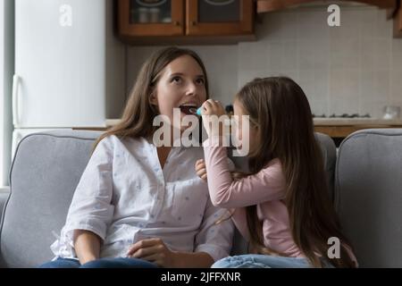 Little daughter plays a doctor, treats her young mother Stock Photo