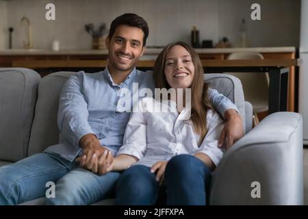 Beautiful married couple rest on couch pose looking at camera Stock Photo