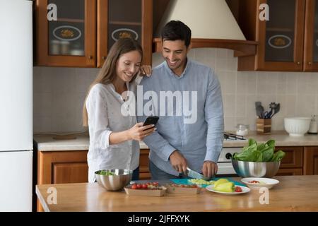 Couple using cellphone making food order while cooking lunch Stock Photo