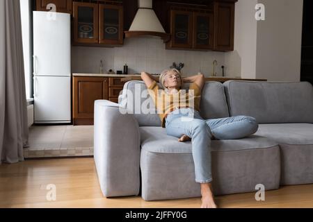 Peaceful older woman leaned on sofa relaxing at home Stock Photo