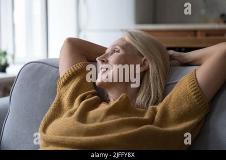 Close up older peaceful woman relaxing leaned on sofa Stock Photo