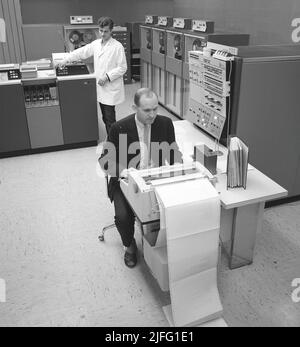 In the 1960s. Interior of a room with computers and people on the job of handling them and register and reading information. A sign above the mainframe computer says IBM 360. IBM system 360 was frequently seen in the american television-series Mad Men.  Picture taken 1965 Kristoffersson ref DY125-10 Stock Photo