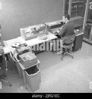 Data handling the 1960s. Interior of a room with IBM computer equipment for reading and entering information into the mainframe computer. A man at a keyboard controls the software, handling, register and reading information. The equipment are parts of an IBM system 360. It was frequently seen in the american television-series Mad Men.  Picture taken 1965 Kristoffersson ref DY127-5 Stock Photo