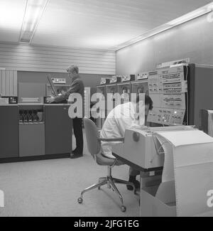 In the 1960s. Interior of a room with computers and people on the job of handling them and register and reading information. A sign above the mainframe computer says IBM 360. IBM system 360 was frequently seen in the american television-series Mad Men.  Picture taken 1965 Kristoffersson ref DY128-9 Stock Photo
