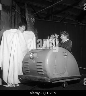 Amusement park in the 1950s. Two women are riding the scary ride and passes a man dressed as a ghost wearing a white sheet. The look surprised and afraid and are holding their hands up in horror. Sweden 1952 Kristoffersson ref Stock Photo